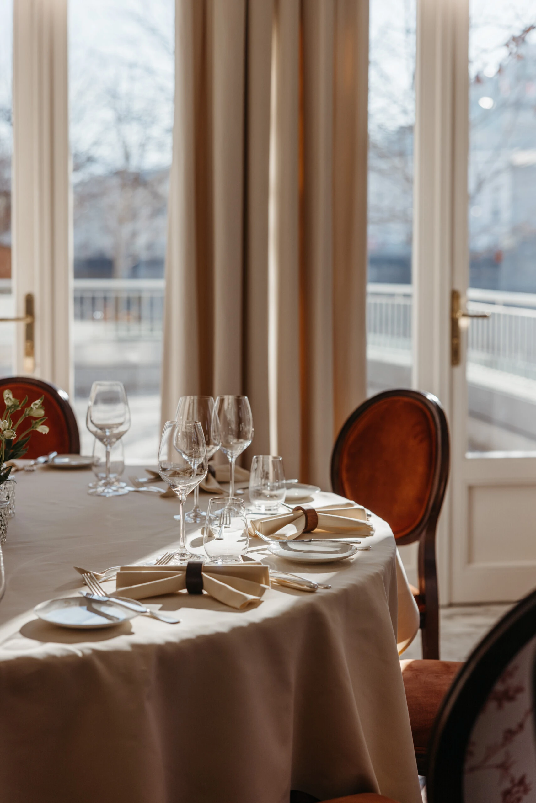 Elegant dining table at Hotel Sacher Salzburg with fine table setting, wine glasses and natural daylight overlooking the Salzach for private events.