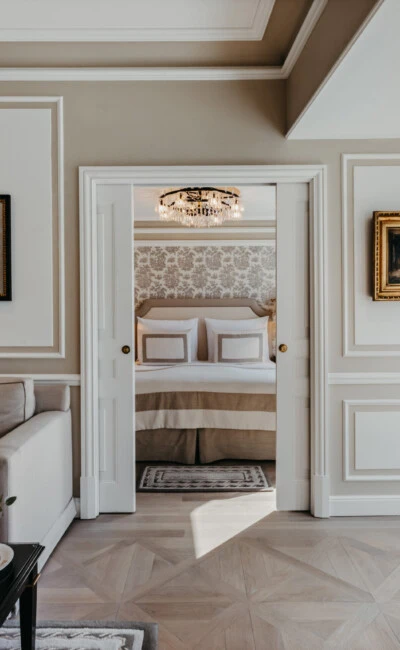 Living area of the Signature Suite with Balcony at Hotel Sacher Salzburg, featuring a sofa, view into the bedroom and large windows