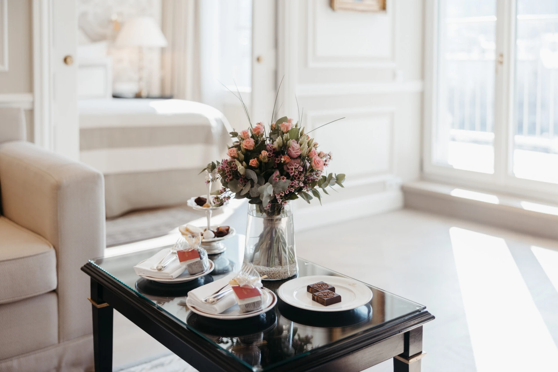 Detail view of the coffee table in the Signature Suite with Balcony at Hotel Sacher Salzburg, featuring fresh flowers and small sweets