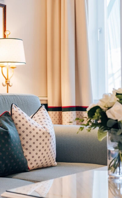 Detail view of the living area in the Signature Suite at Hotel Sacher Salzburg, featuring a sofa, decorative cushions, fresh flowers and classic interior design.