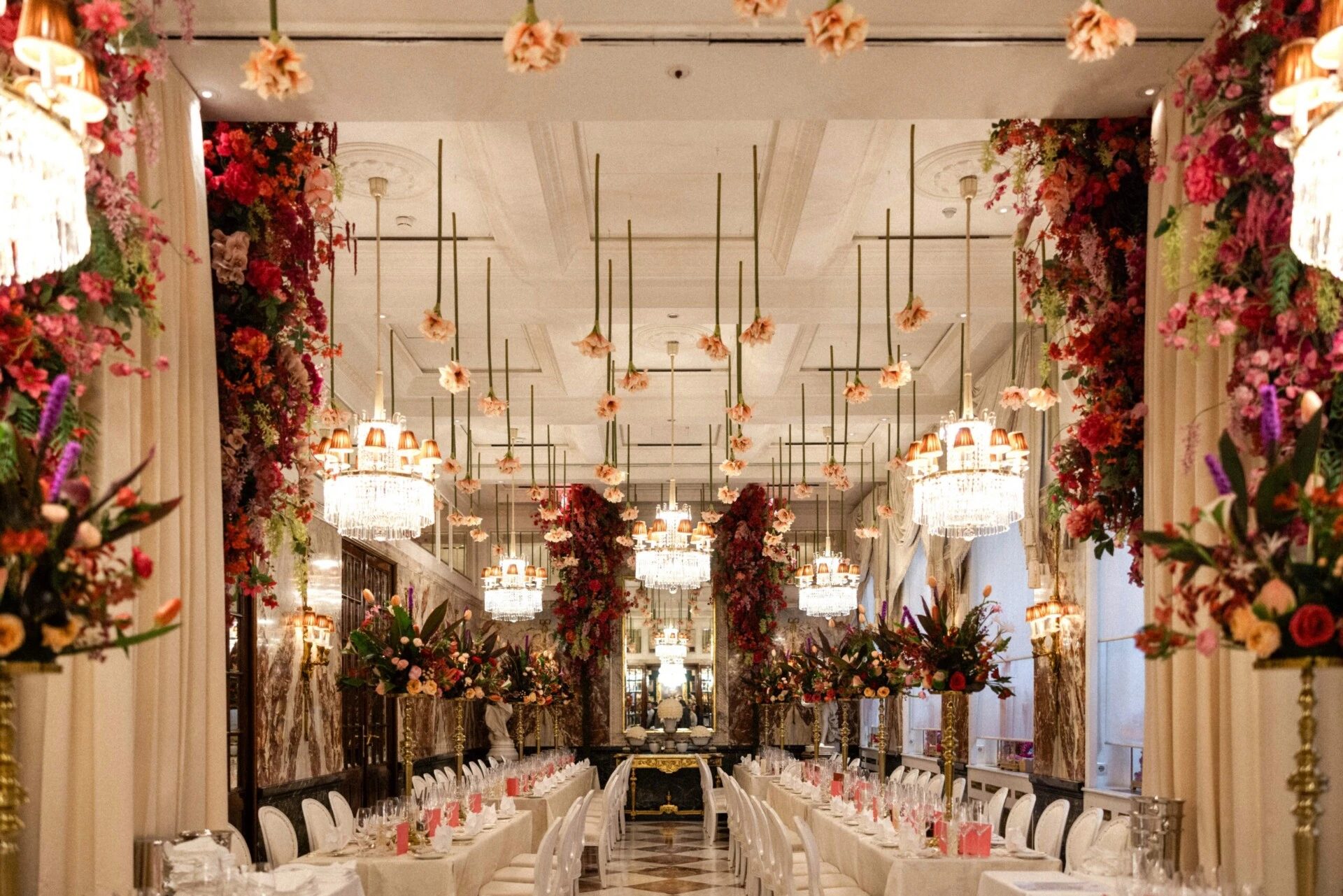 Festively decorated Marble Hall at Hotel Sacher Vienna with long dining tables, crystal chandeliers and abundant floral arrangements.