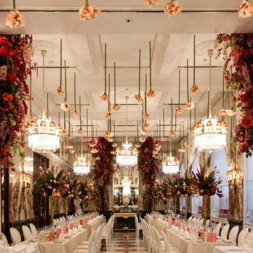 Festively decorated Marble Hall at Hotel Sacher Vienna with long dining tables, crystal chandeliers and abundant floral arrangements.