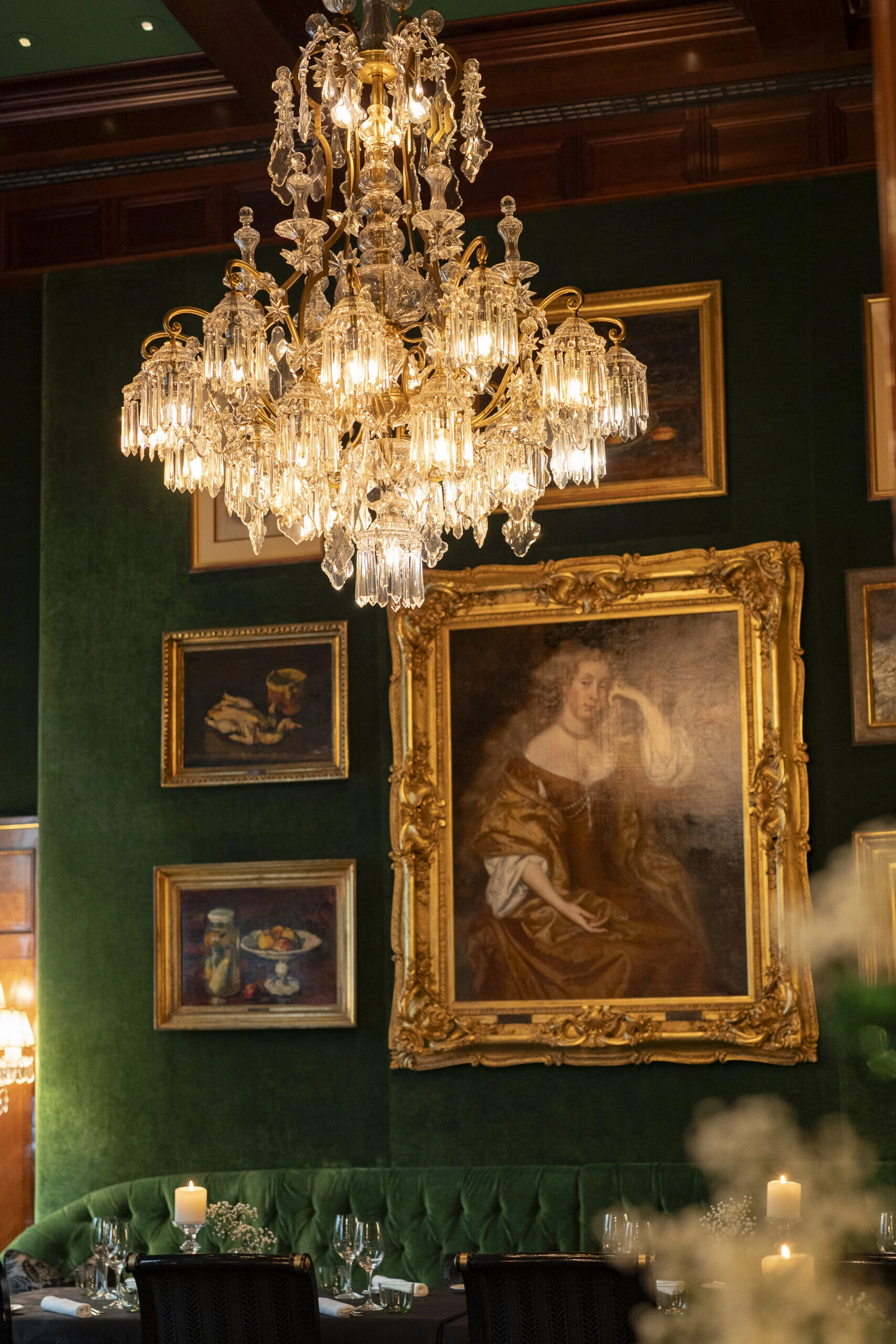 Crystal chandelier and historic paintings in the RestaurantGrüne Bar at Hotel Sacher Vienna.