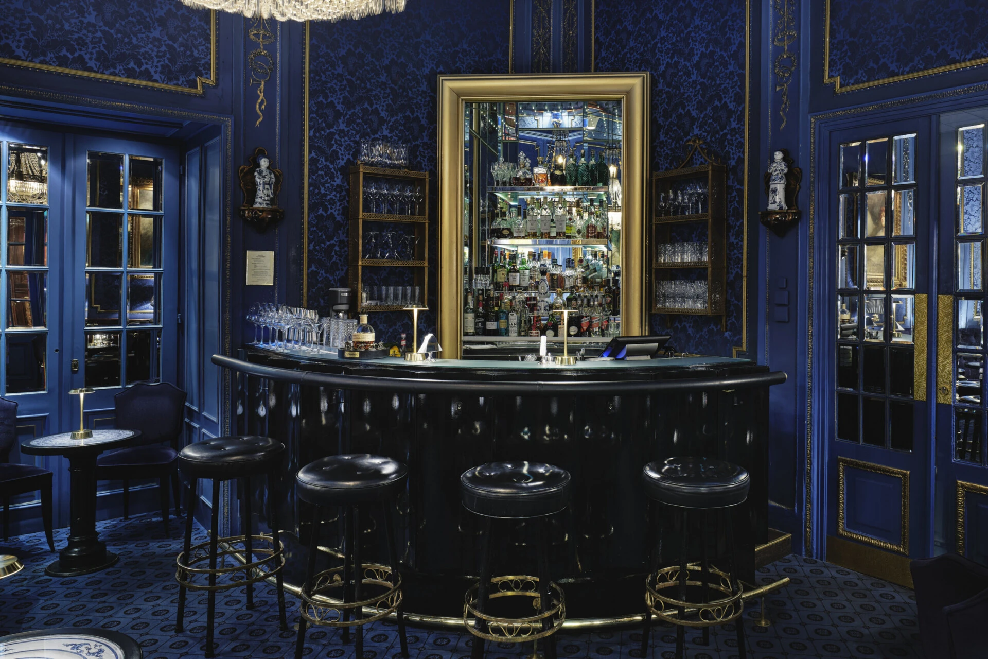 Elegant Blaue Bar with a dark counter, gold accents and an illuminated selection of spirits.