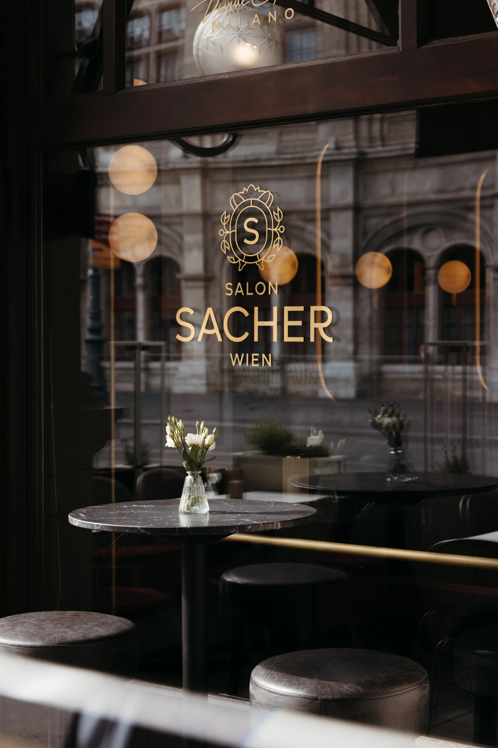 View through the window featuring the golden Salon Sacher Vienna logo.