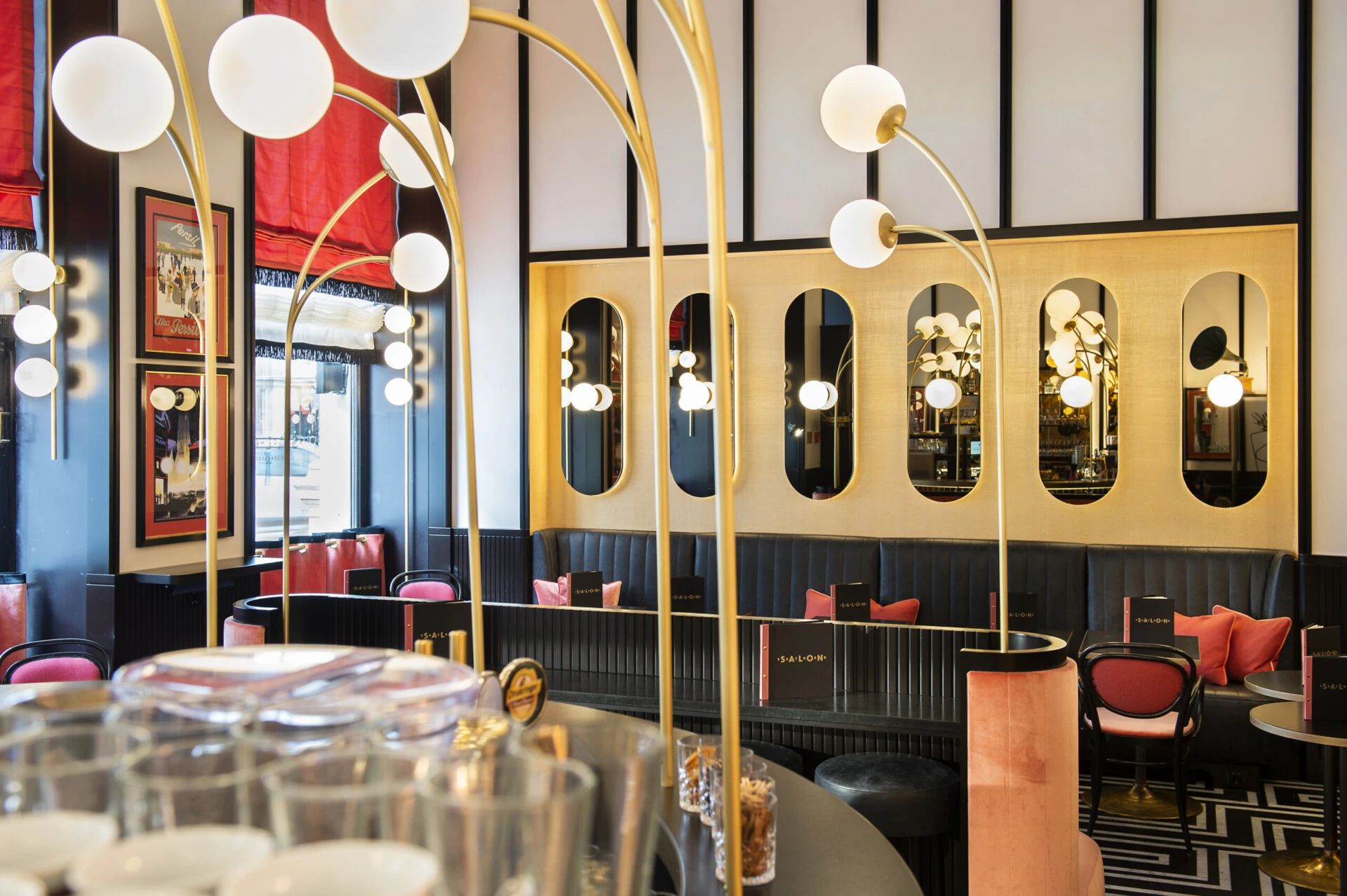Stylish interior of Salon Sacher with golden lights, mirrors and red seating accents.