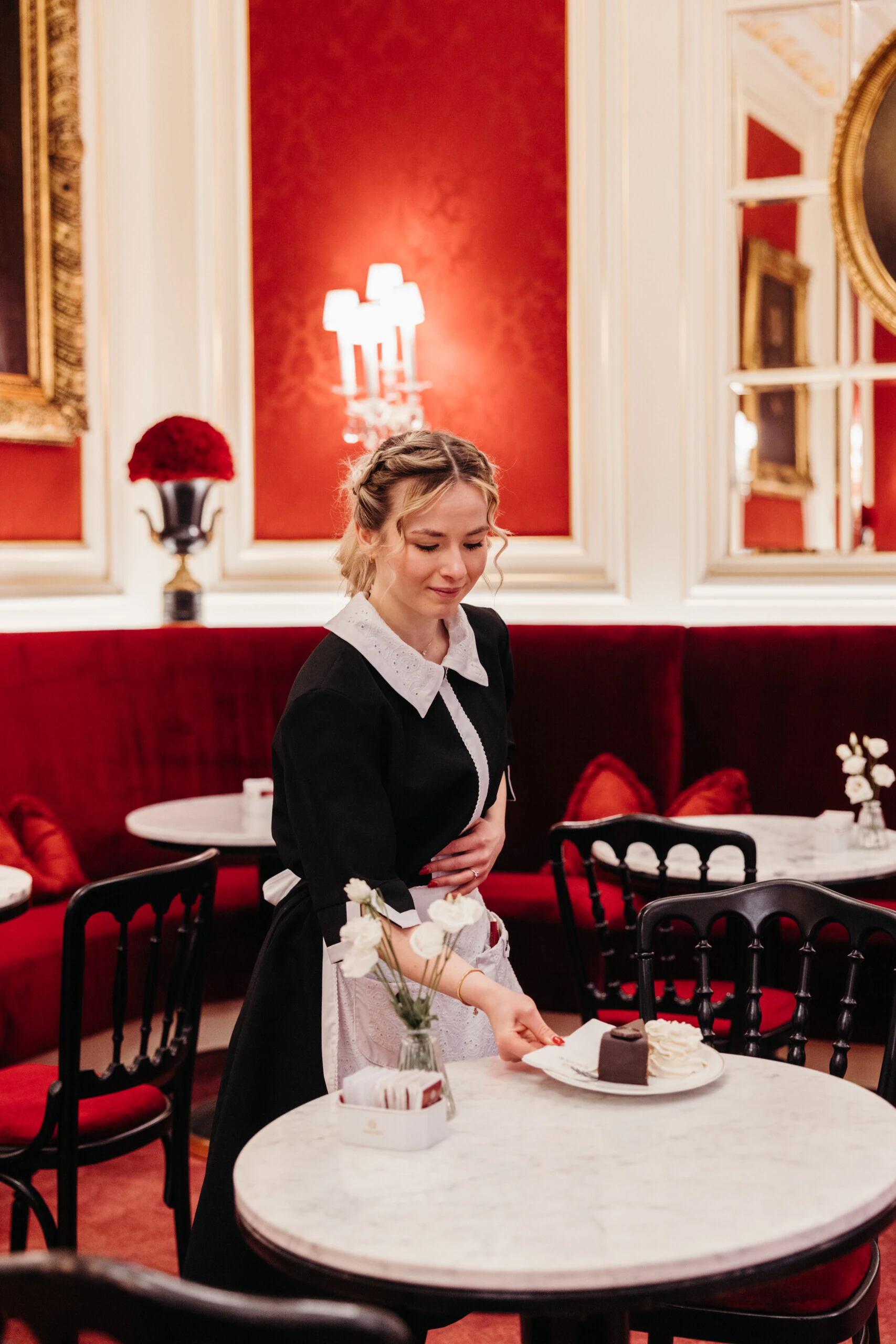 Staff member serving Original Sacher-Torte with whipped cream at Café Sacher Vienna.