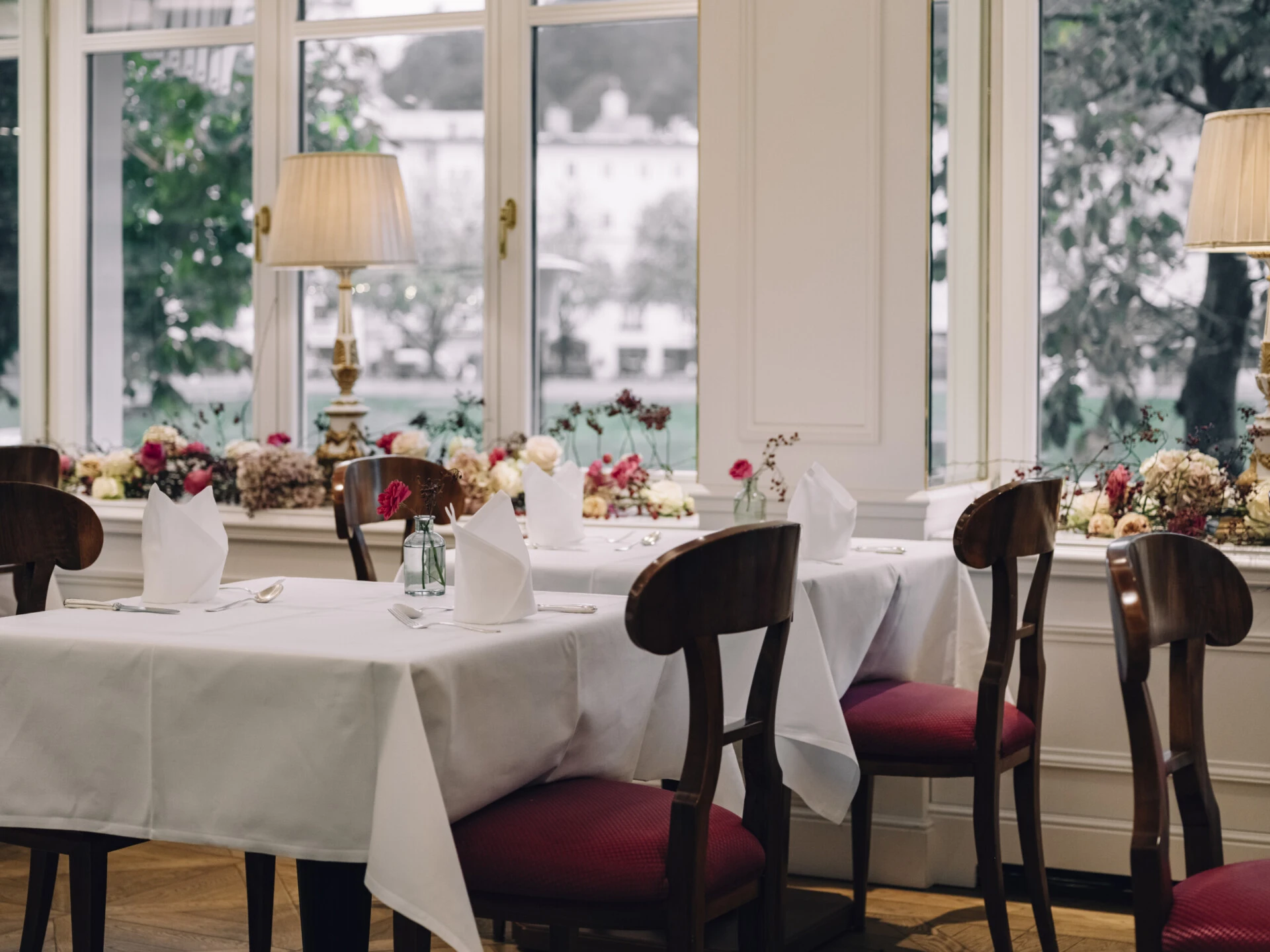 Elegantly set tables in the Salzachzimmer with views of the greenery.