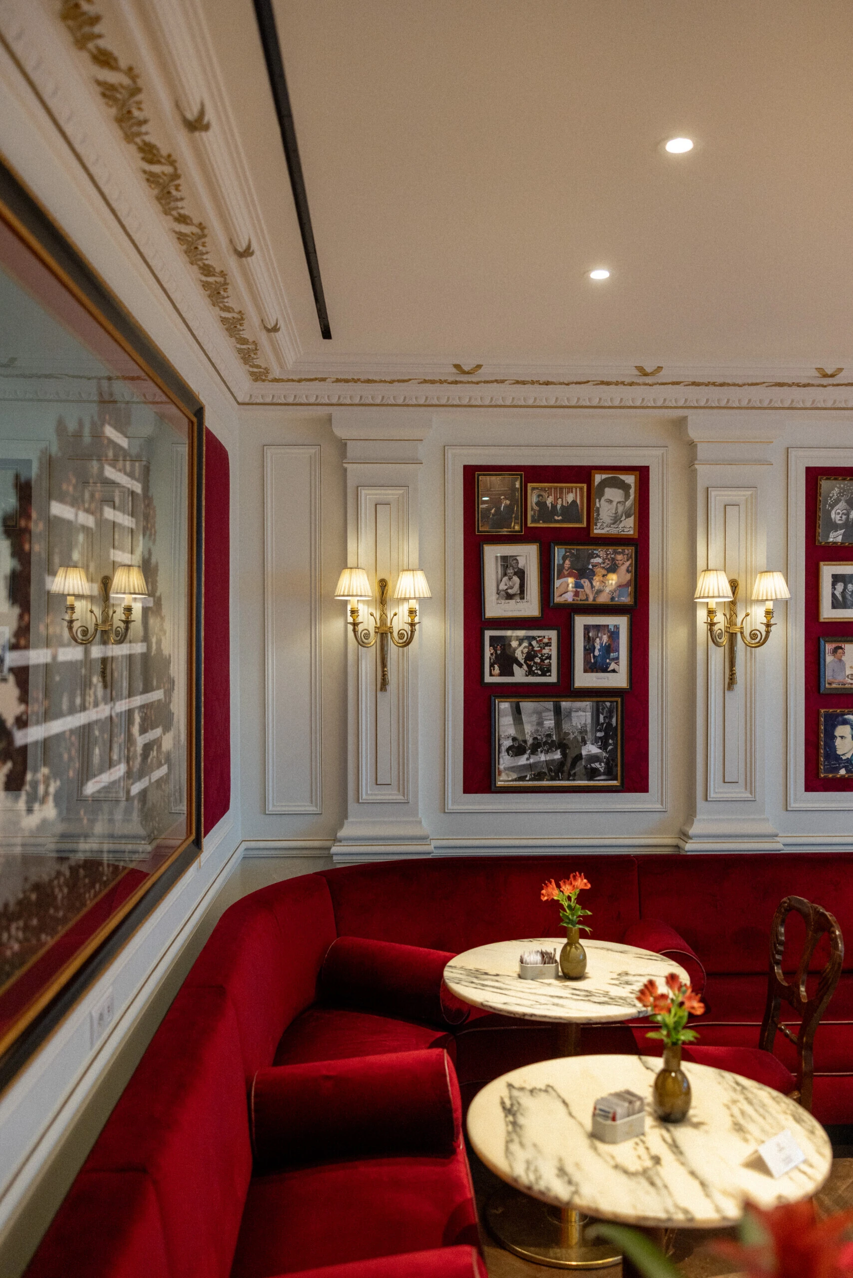 Cosy seating area with red upholstery, flowers and framed photographs.