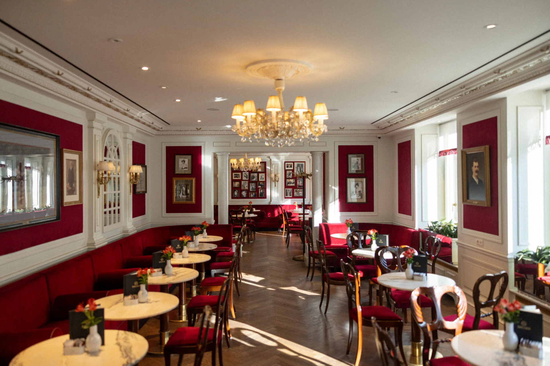 Bright dining room at Café Sacher Salzburg with red seating and chandeliers.