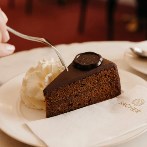Close-up of a slice of Original Sacher-Torte with unsweetened whipped cream.