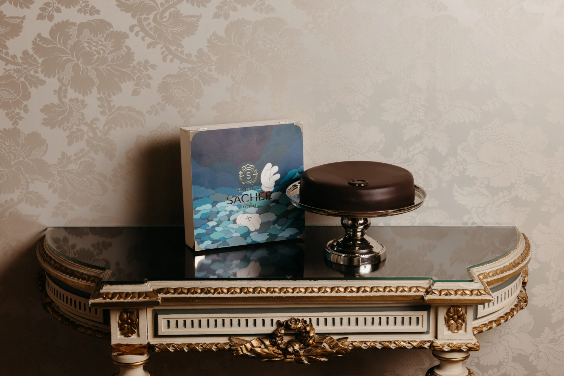 Original Sacher-Torte with artist-designed packaging by KAWS displayed on an elegant console.