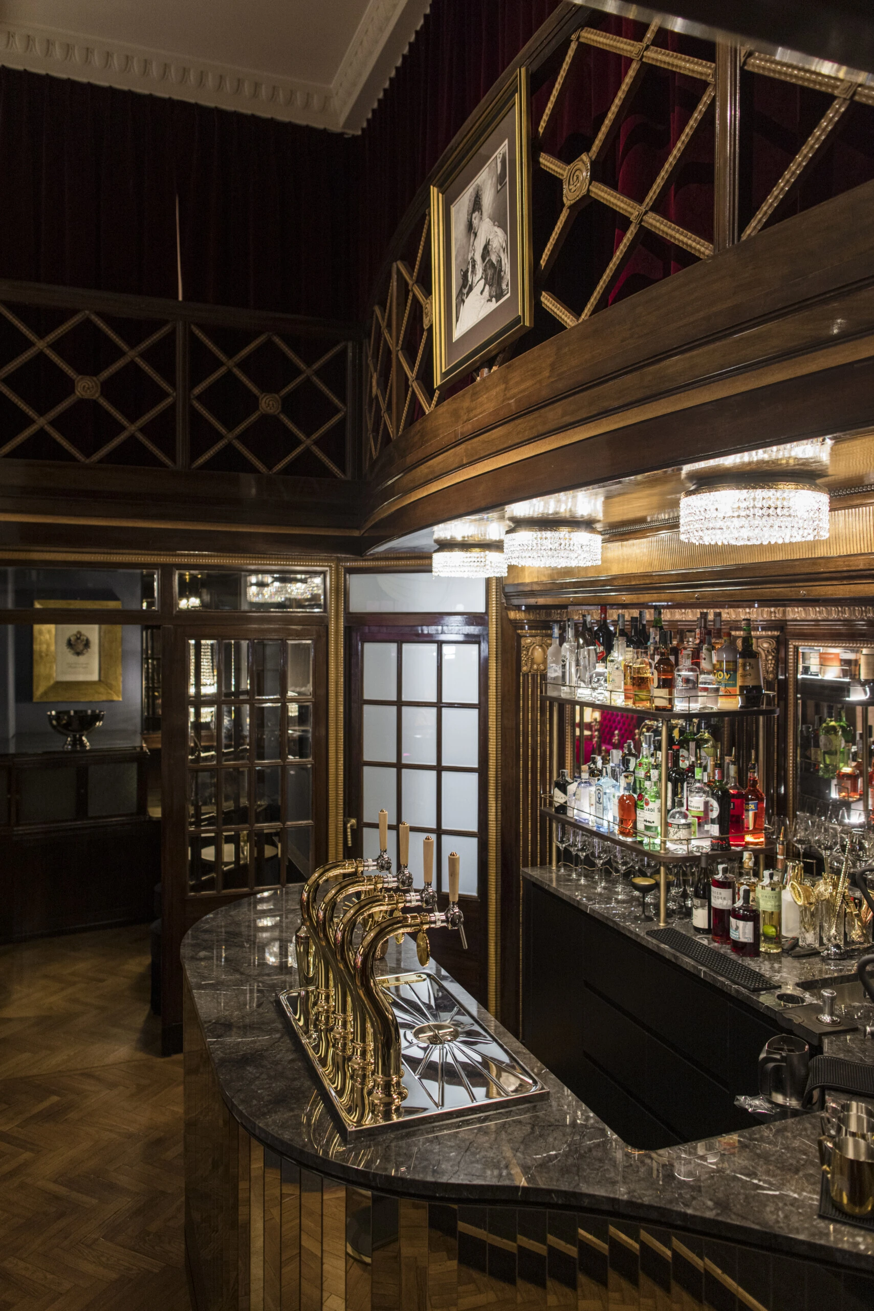 Elegant bar counter at Caffè Sacher Trieste with a marble surface and golden taps.