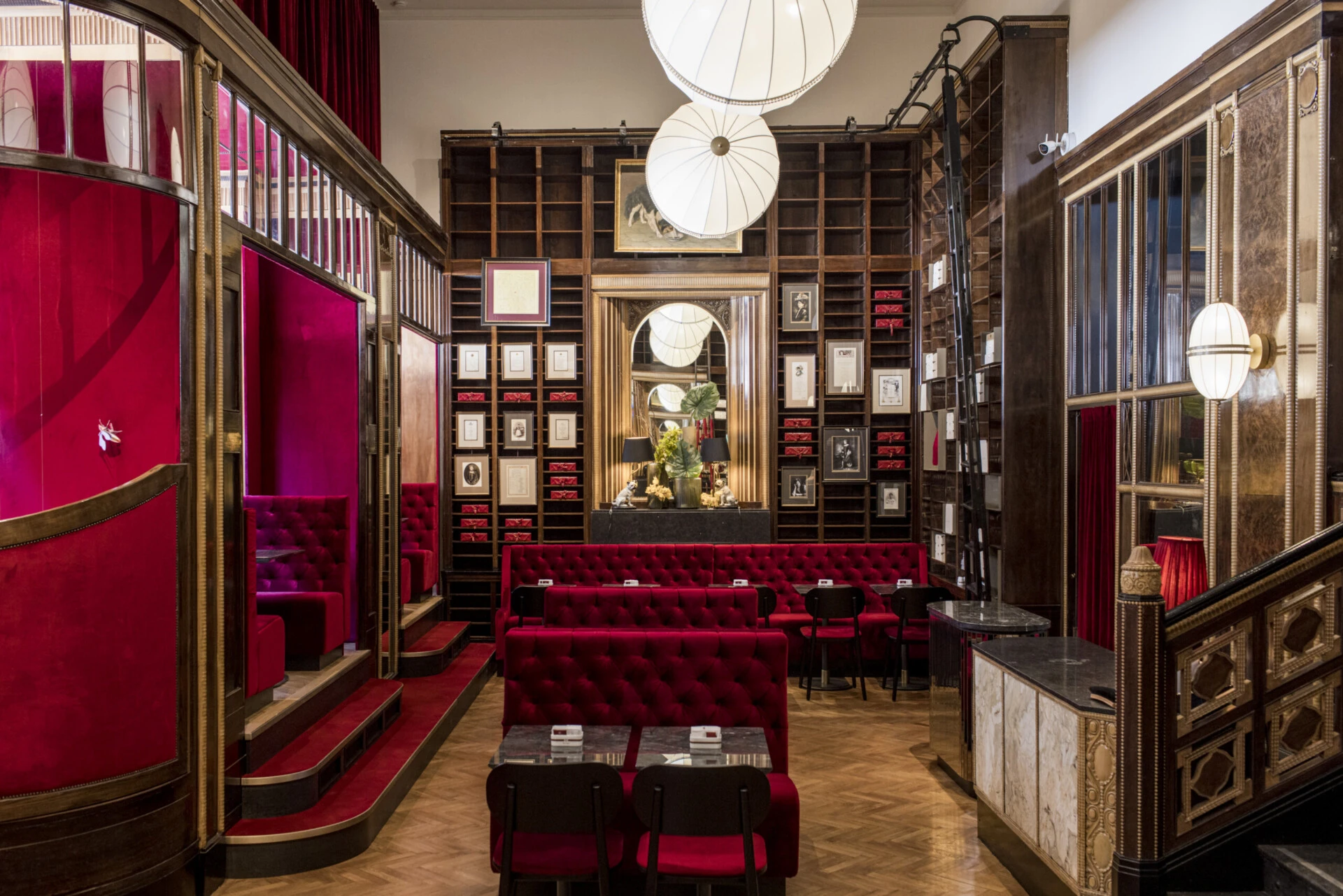 Full view of Caffè Sacher Trieste with red seating and elegant wood panelling.