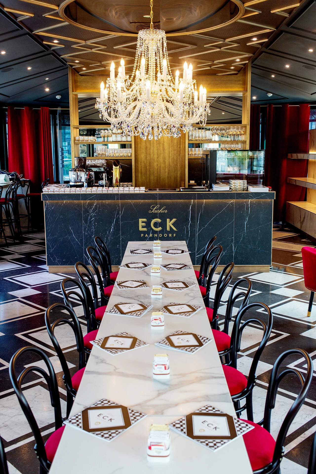Elegant interior of Sacher Eck Parndorf with a chandelier and long dining table.