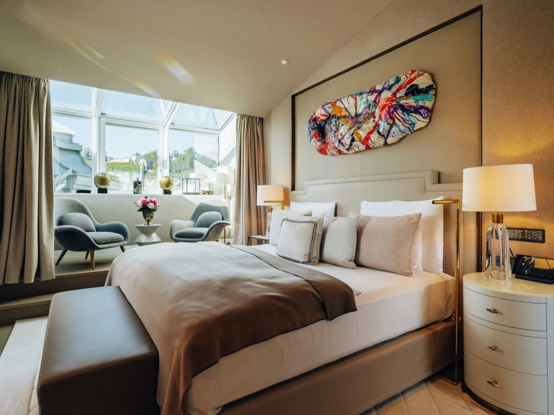 Modern bedroom in the Sky Suite with a double bed, seating area and panoramic windows.