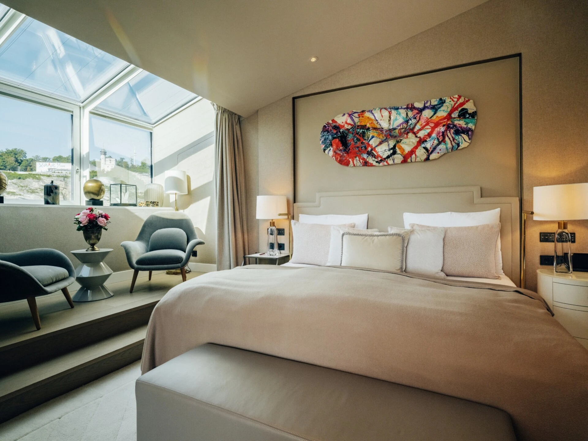 Modern bedroom in the Sky Suite with a double bed, seating area and panoramic windows.