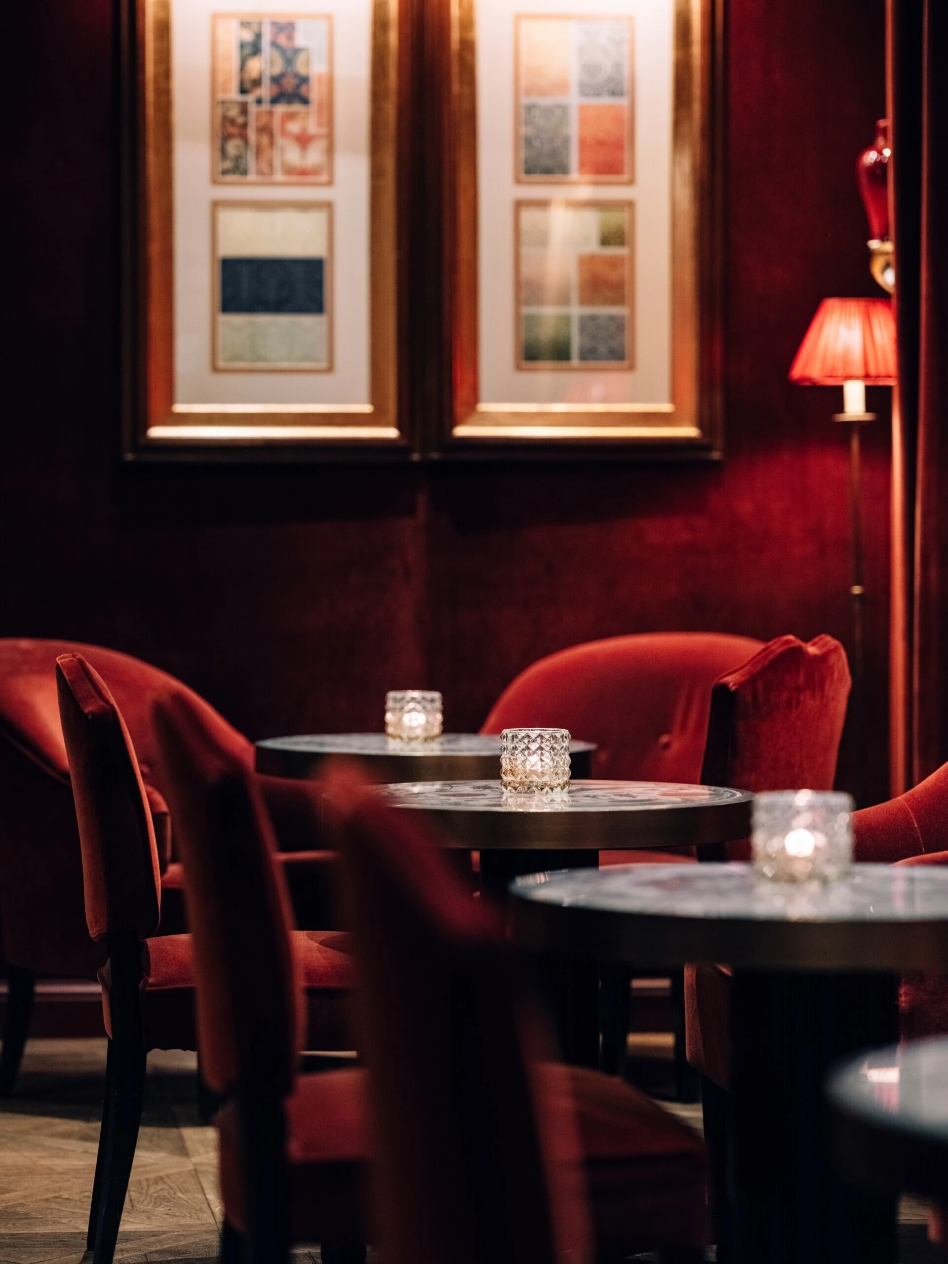 mall bar table with candlelight and a red velvet chair.