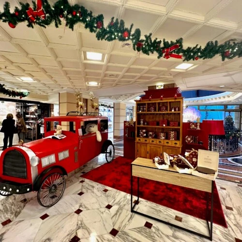 Hotel Sacher pop-up store in Monaco featuring a decorative vintage red car, festive Original Sacher-Torte gift boxes, and holiday decorations.
