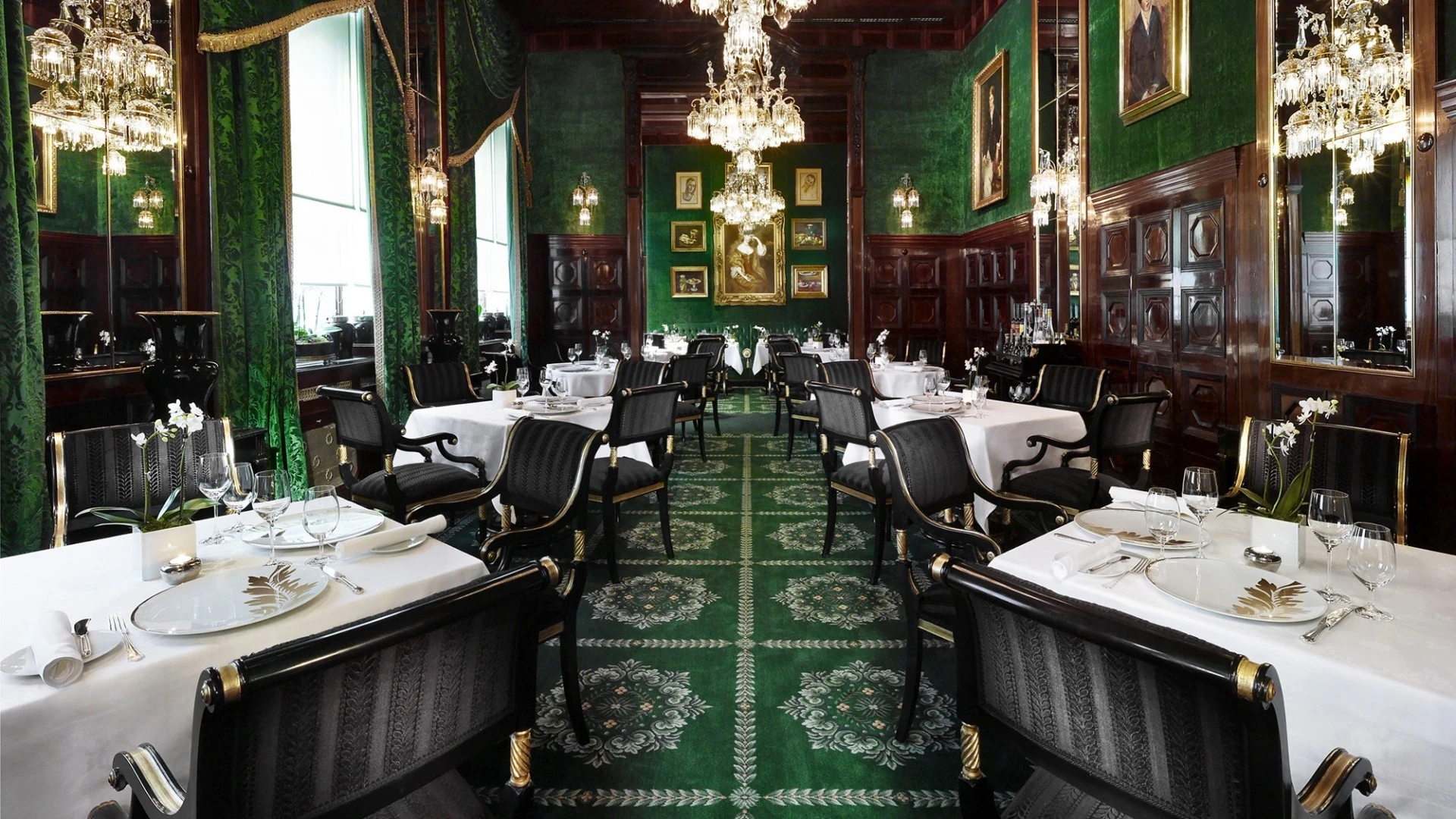 The elegant, vintage-style dining room with green decor, white tablecloths, and ornate black-and-gold chairs named Restaurant Grüne Bar.