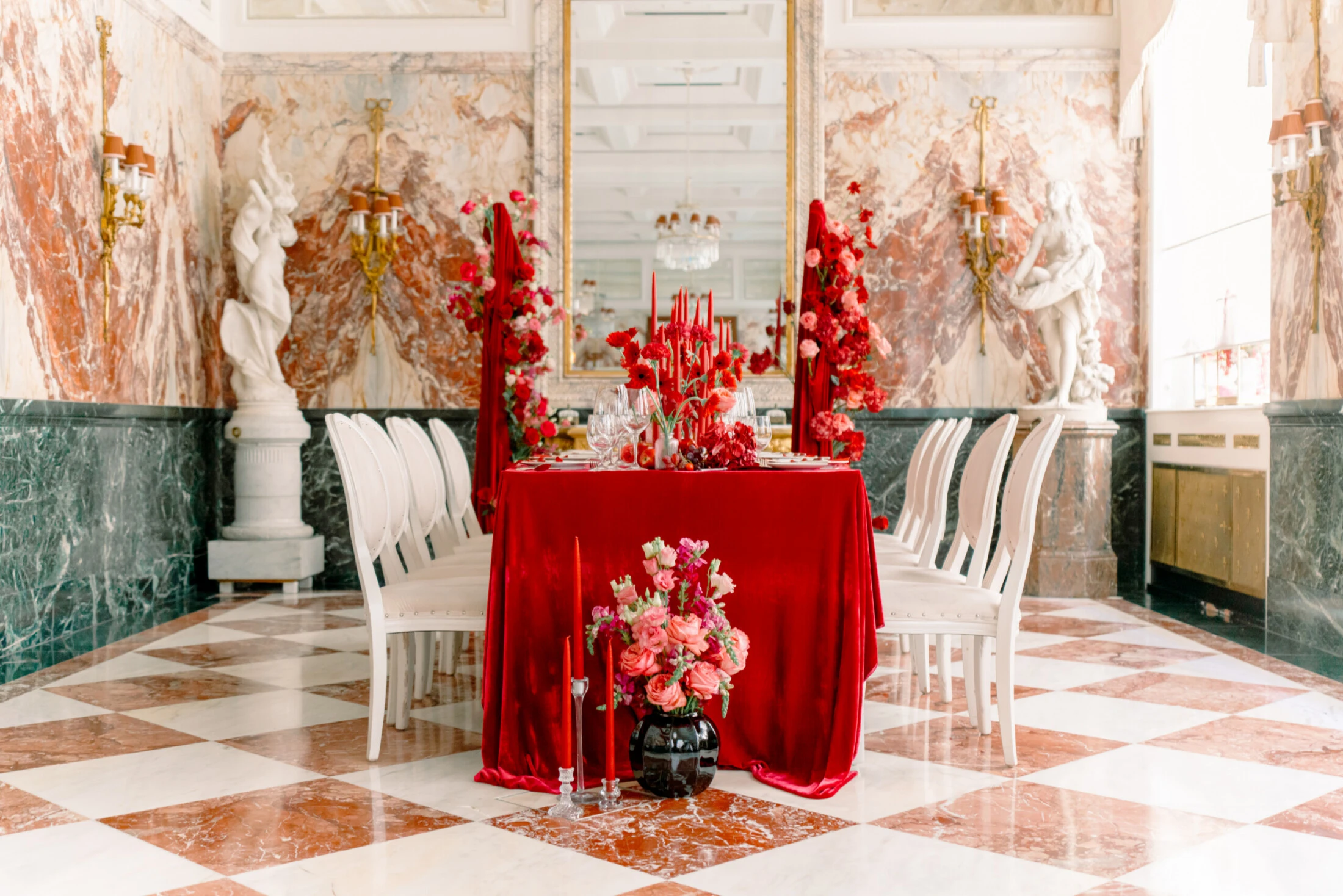 A festively set wedding table with red floral arrangements in the Marble Hall of the Hotel Sacher Vienna.