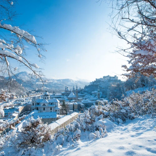 Winter view over Salzburg’s snow-covered Old Town with Hohensalzburg Fortress in the background.
