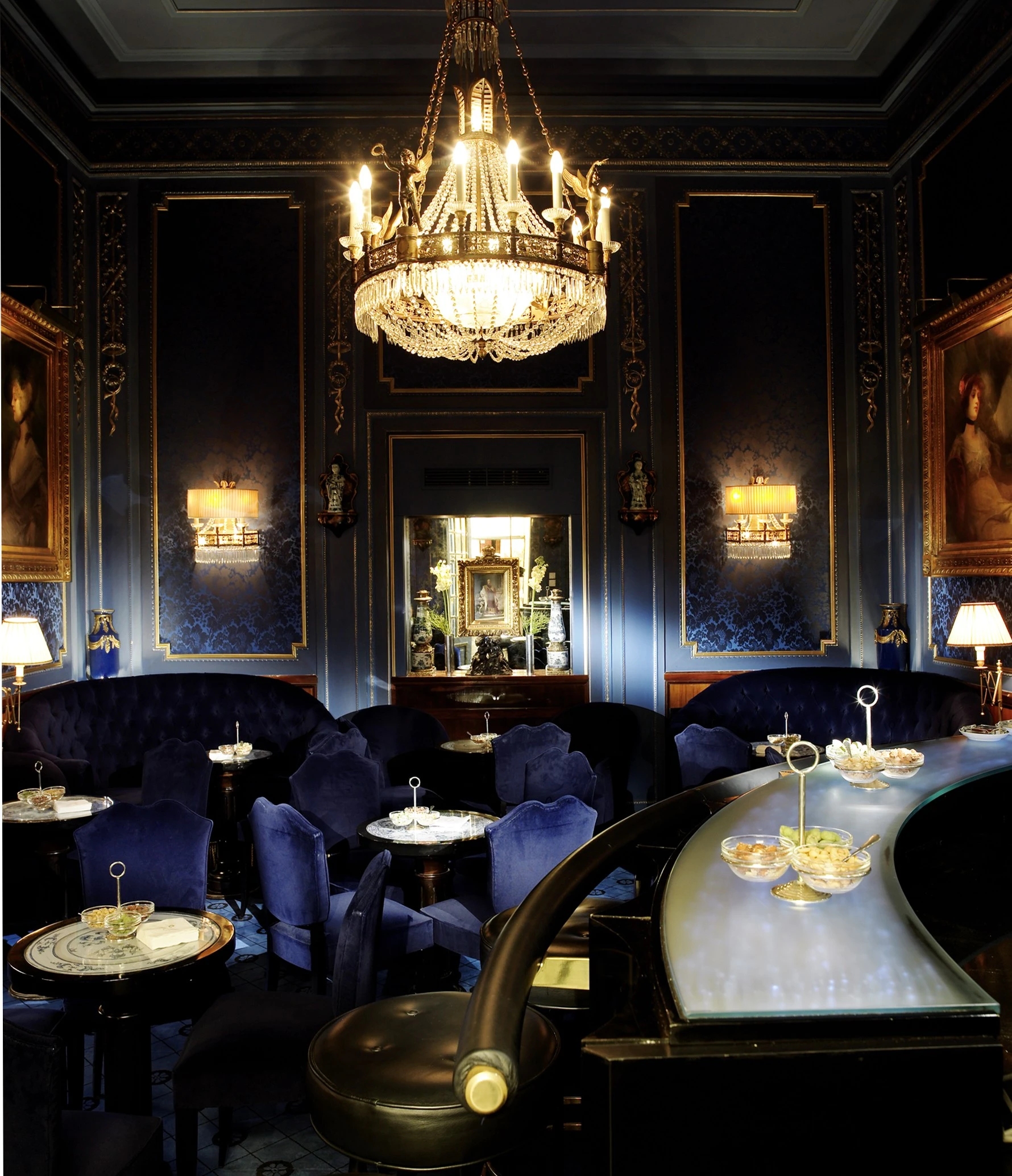 The Blaue Bar with deep blue velvet seating, ornate wallpaper, and a classical portrait in a golden frame.