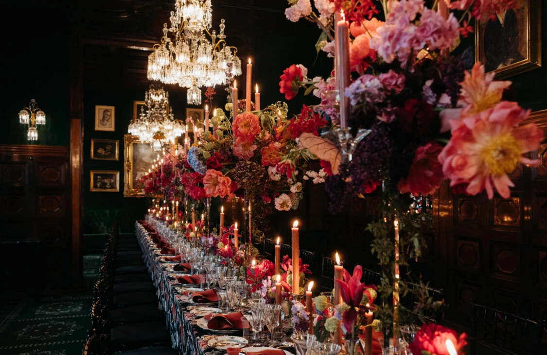 Festive table setting in the Restaurant Grüne Bar at Hotel Sacher Vienna with abundant flowers, candles and crystal chandeliers.