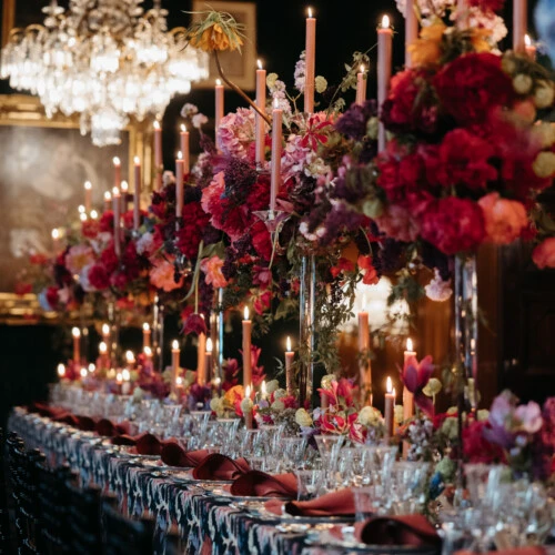 Festive table setting in the Restaurant Grüne Bar at Hotel Sacher Vienna with abundant flowers, candles and crystal chandeliers.