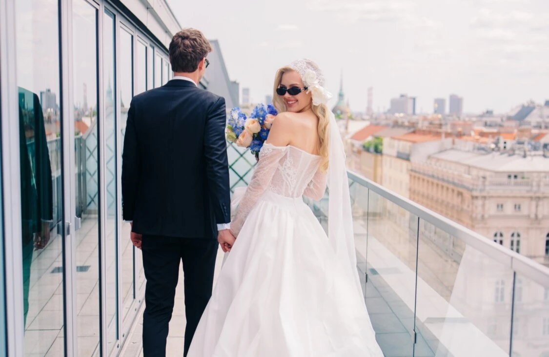 A bride and groom on the terrace of the Hotel Sacher Vienna, looking out over the rooftops of Vienna.