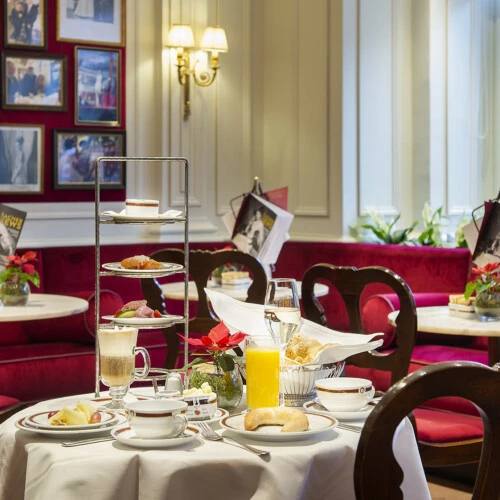 A beautifully set table at Café Sacher Salzburg showcases an elegant breakfast with pastries, juice, and coffee.