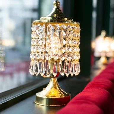 A crystal-adorned lamp casts a warm glow over a plush red velvet seat.