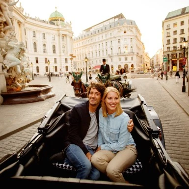 A happy couple enjoys a romantic carriage ride through historic Vienna.