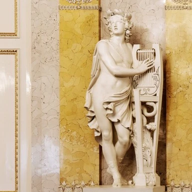 A marble statue of Apollo stands gracefully with a lyre in the Albertina’s elegant interior.