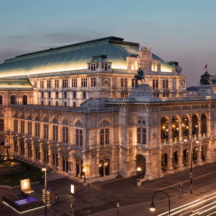 Vienna State Opera beautifully illuminated at twilight, standing as a centerpiece in the bustling cityscape.