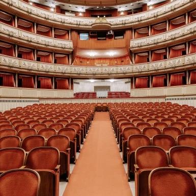 richly upholstered interior seating of the Vienna State Opera, with red velvet chairs and elegant balconies.