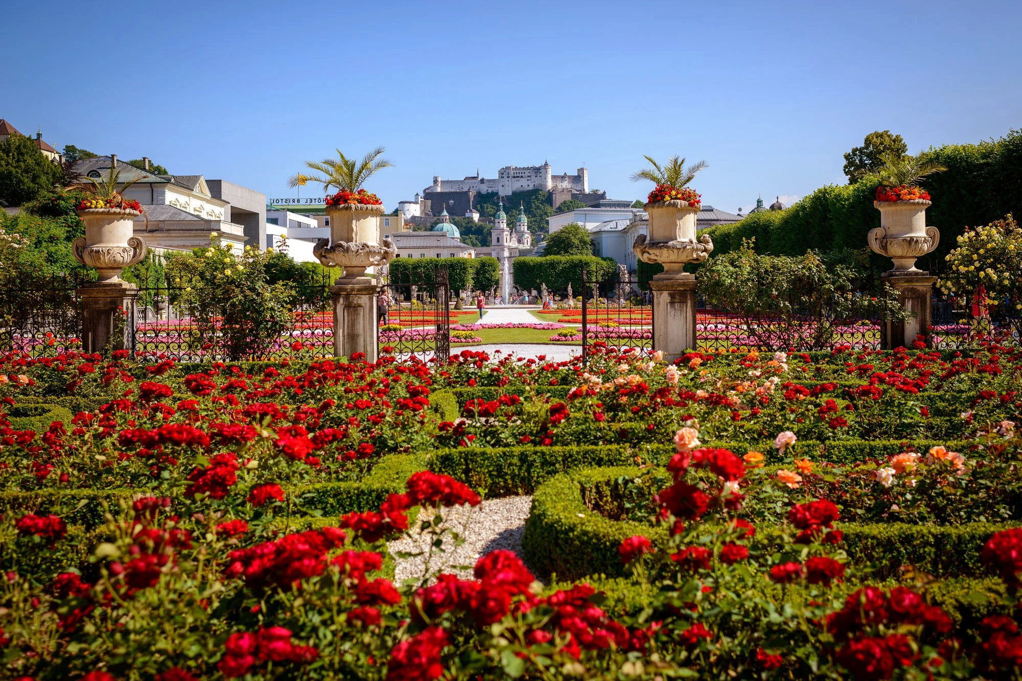 Mirabell Gardens bloom with vibrant flowers, framing a perfect view of Salzburg Cathedral and Hohensalzburg Fortress.