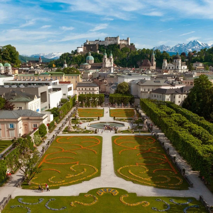 Mirabell Gardens bloom with vibrant flowers, framing a perfect view of Salzburg Cathedral and Hohensalzburg Fortress.