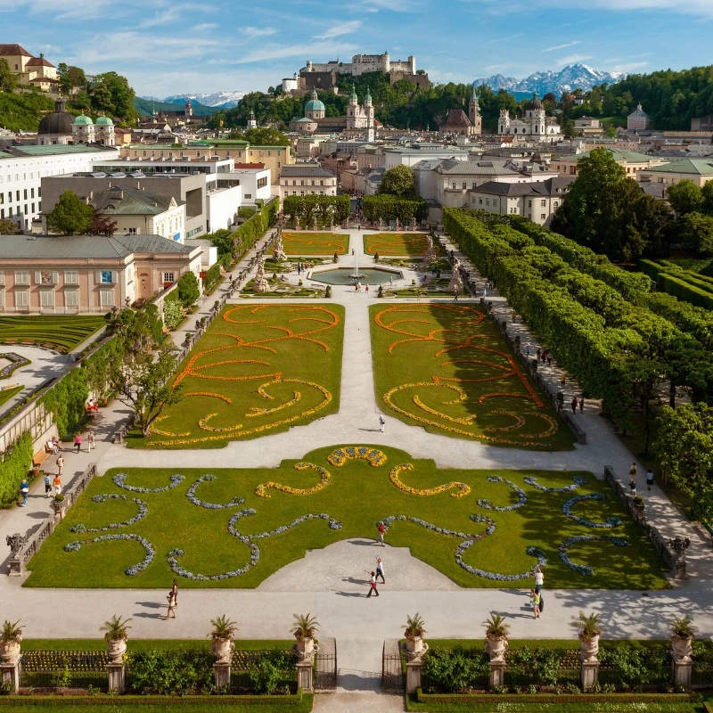 Mirabell Gardens bloom with vibrant flowers, framing a perfect view of Salzburg Cathedral and Hohensalzburg Fortress.