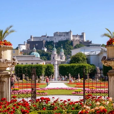 Mirabell Gardens bloom with vibrant flowers, framing a perfect view of Salzburg Cathedral and Hohensalzburg Fortress.