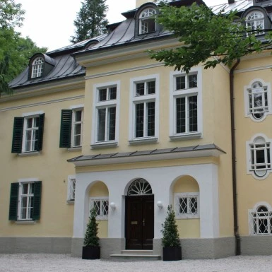 This image shows a charming yellow villa featured on *The Original Sound of Music Tour*, famously known as one of the filming locations from the classic movie.