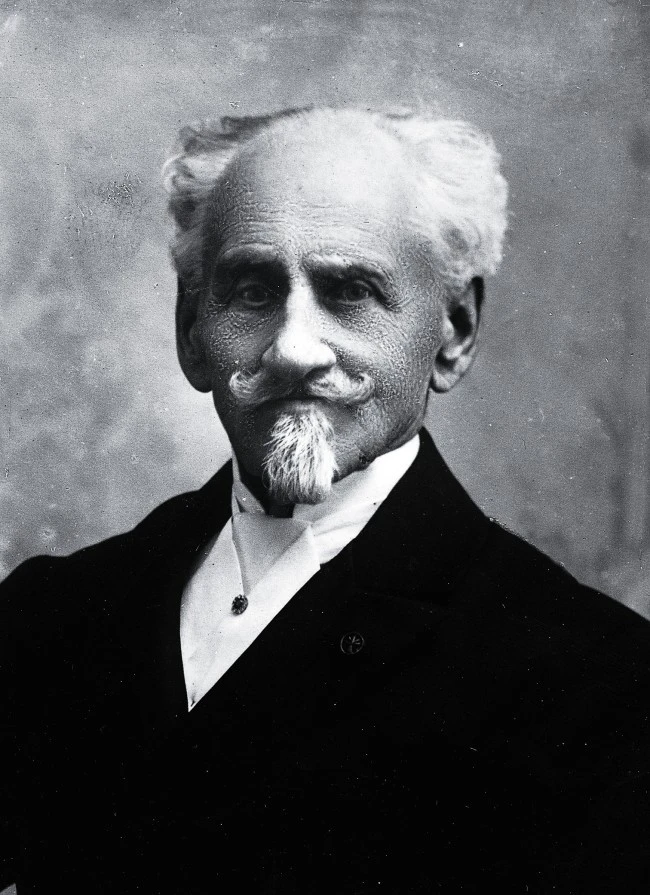 This black-and-white portrait shows Franz Sacher in formal attire, with his signature mustache and goatee, exuding dignified elegance and historical significance.