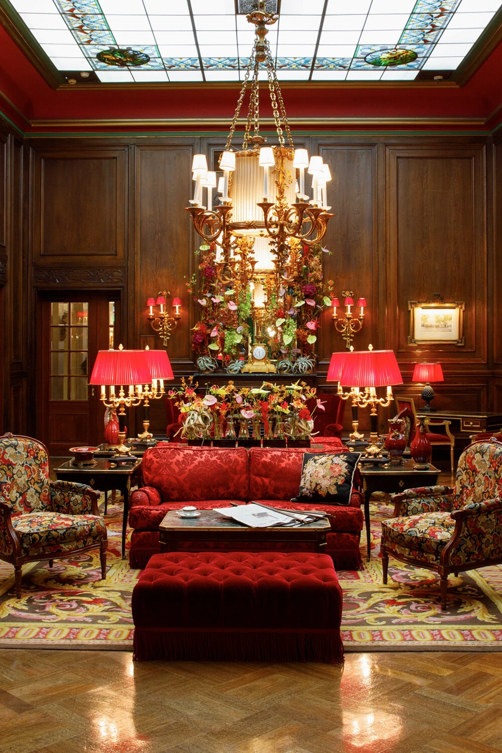 The lobby at Hotel Sacher radiates timeless elegance with its opulent red furnishings, floral displays, and classic Viennese charm.