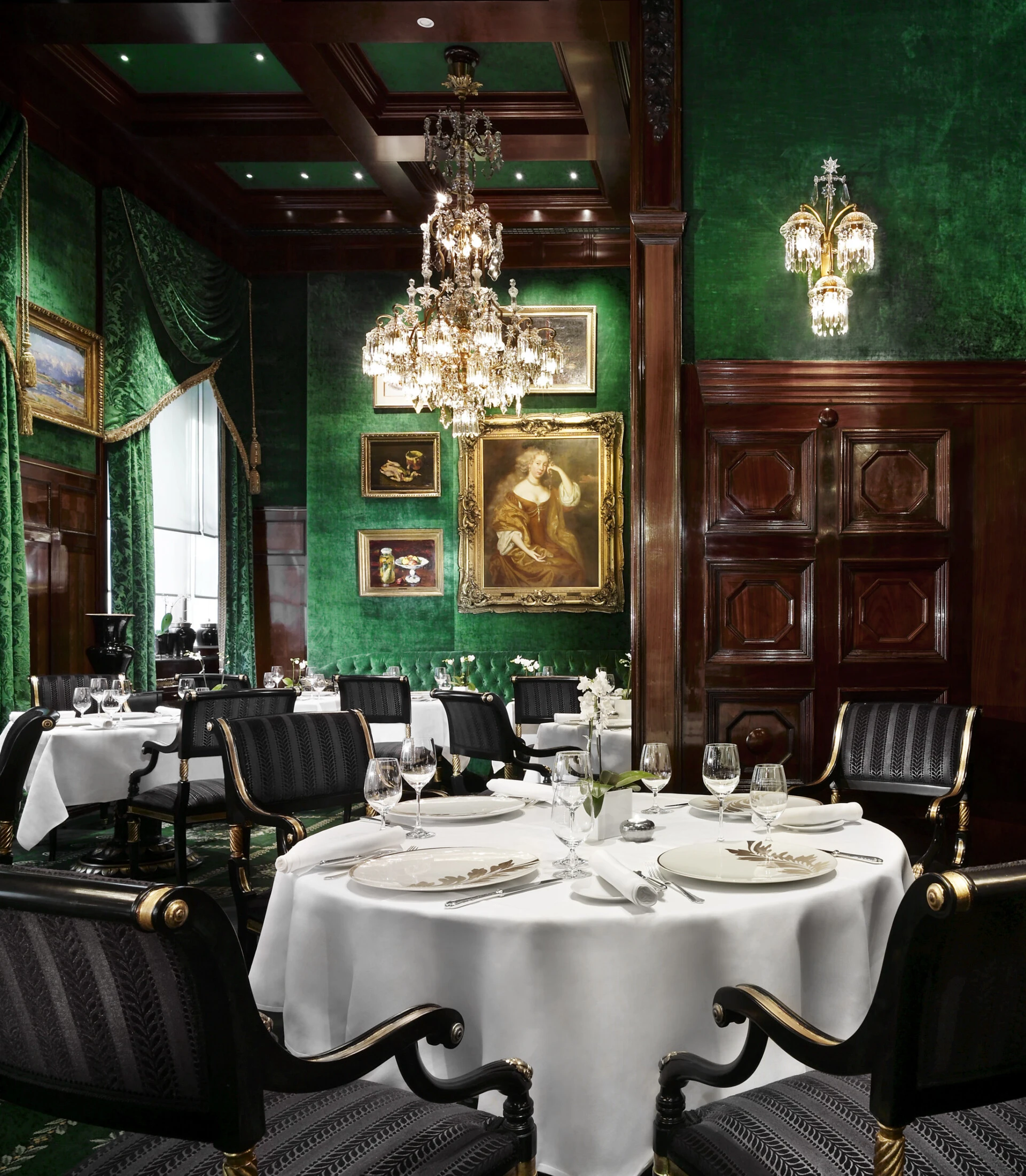 This is the elegant Restaurant Grüne Bar, with green velvet walls, classic paintings, and crystal chandeliers.