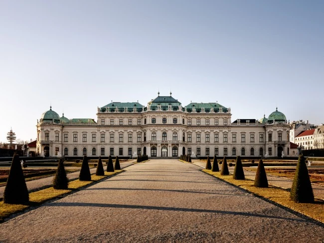 The majestic Upper Belvedere Palace in Vienna stands symmetrically at the end of a formal garden path.