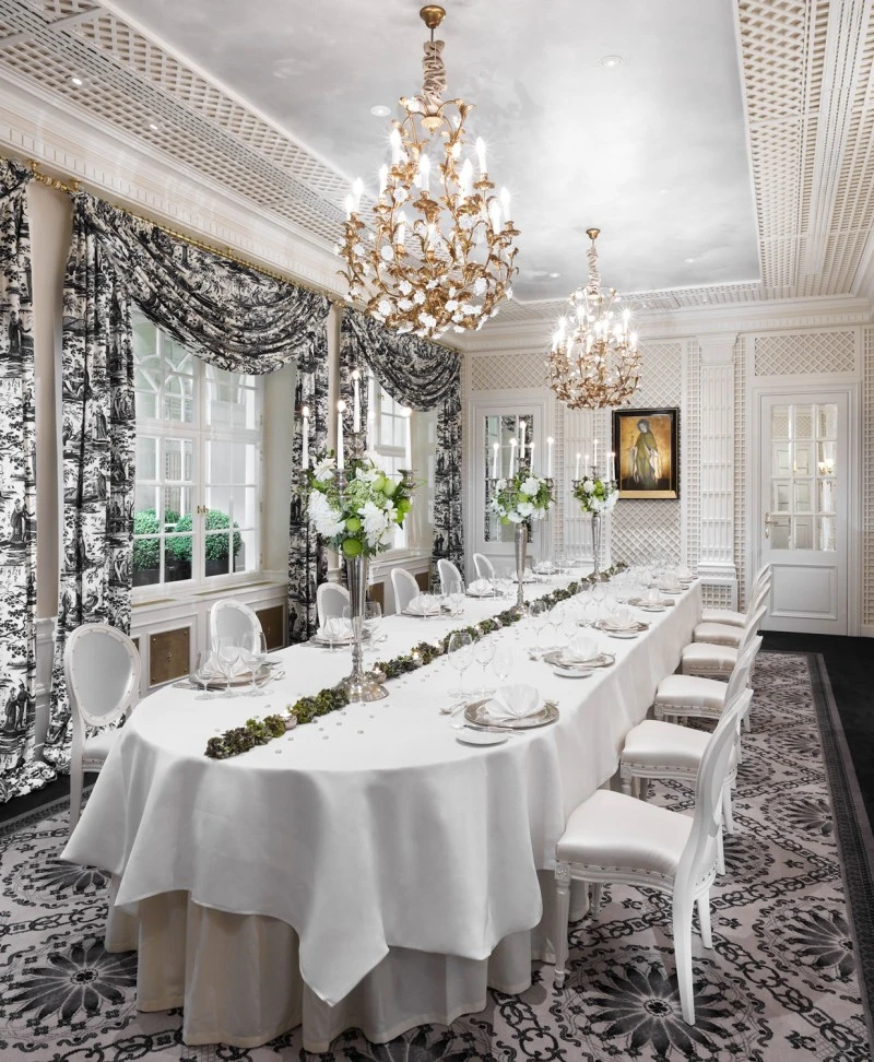 A luxurious white-themed dining room with floral arrangements, chandeliers, and elegant decor.