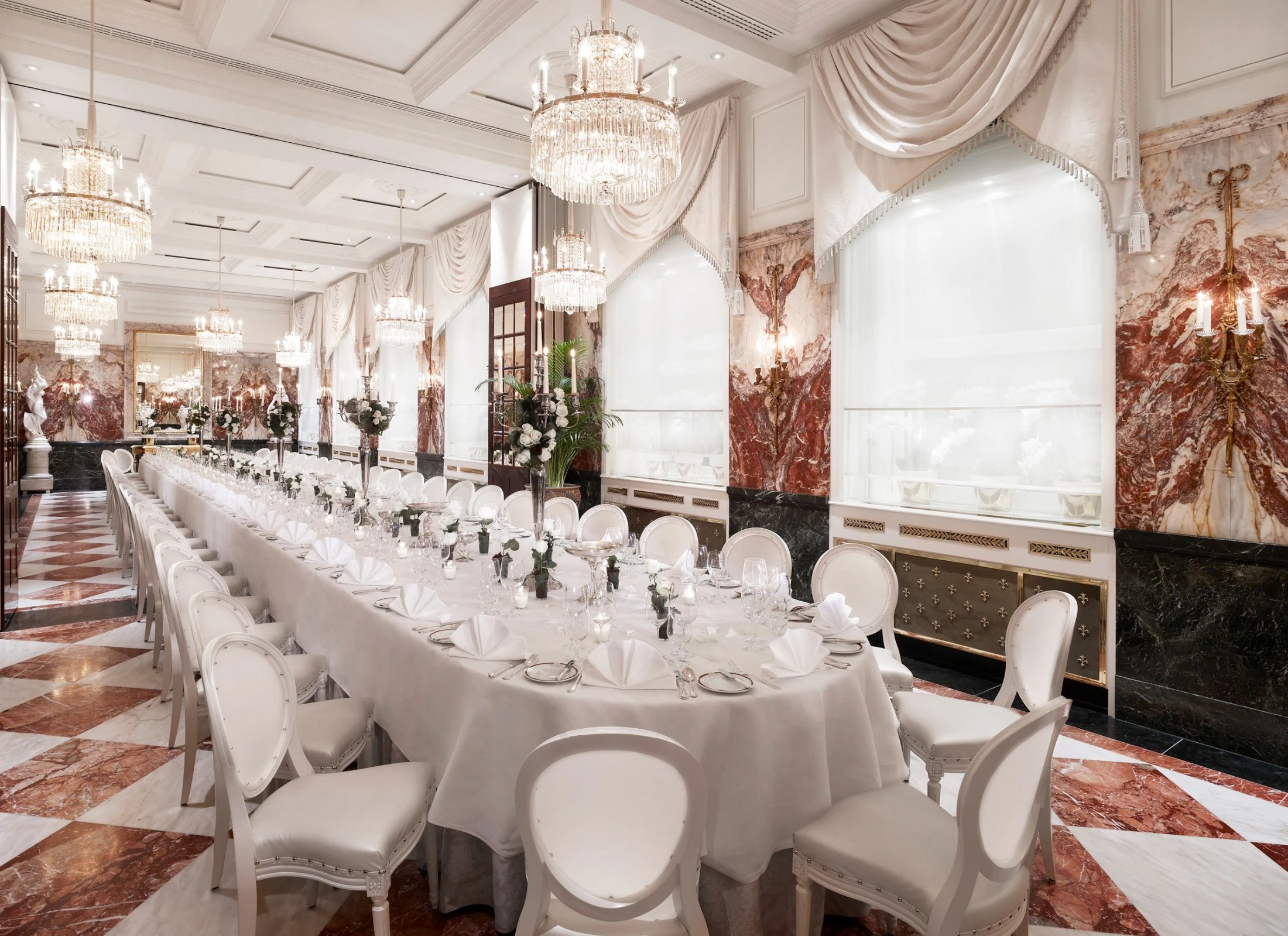 Banquet room at Hotel Sacher Salzburg, featuring a long table with formal place settings and grand chandeliers.