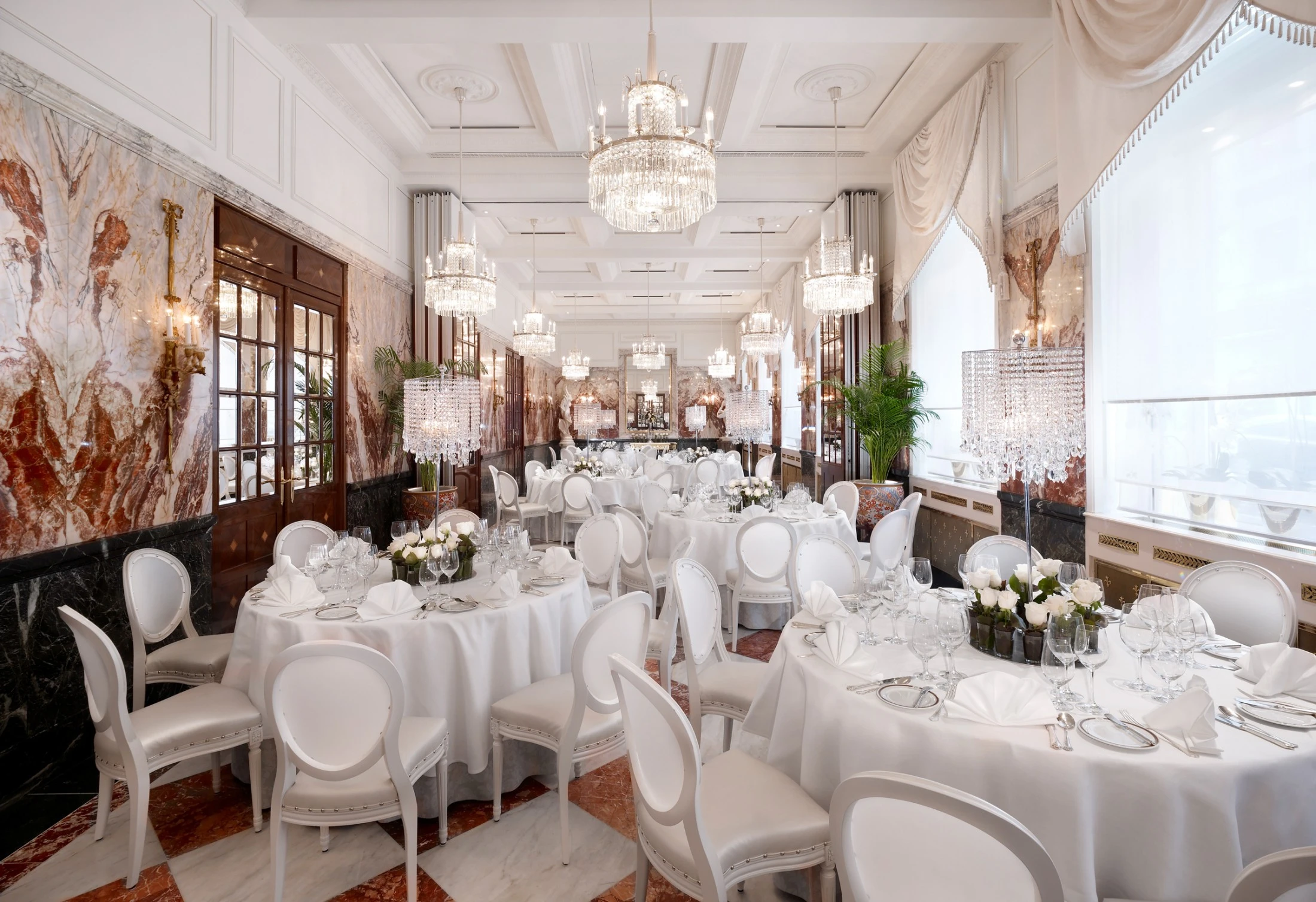The luxurious Marmorsaal features elegant chandeliers, marble walls, and white-clothed tables set for fine dining.