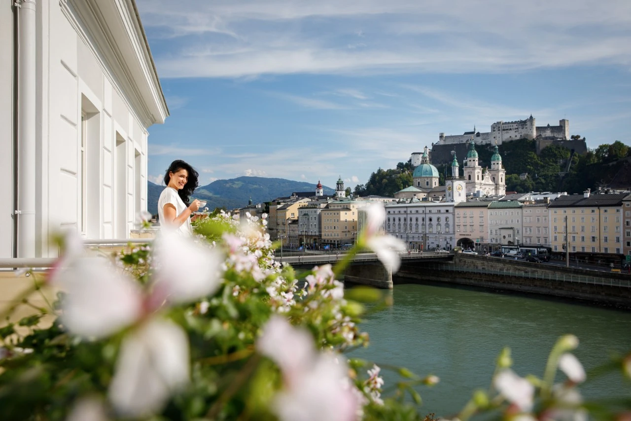 A serene moment on the balcony, overlooking the Salzach River and the historic skyline of Salzburg crowned by the Hohensalzburg Fortress.