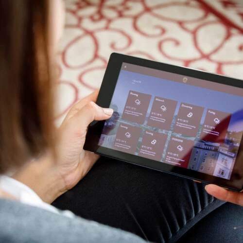 This image shows a guest using a SuitePad tablet to access hotel information and weather updates, showcasing the convenience of digital in-room services.